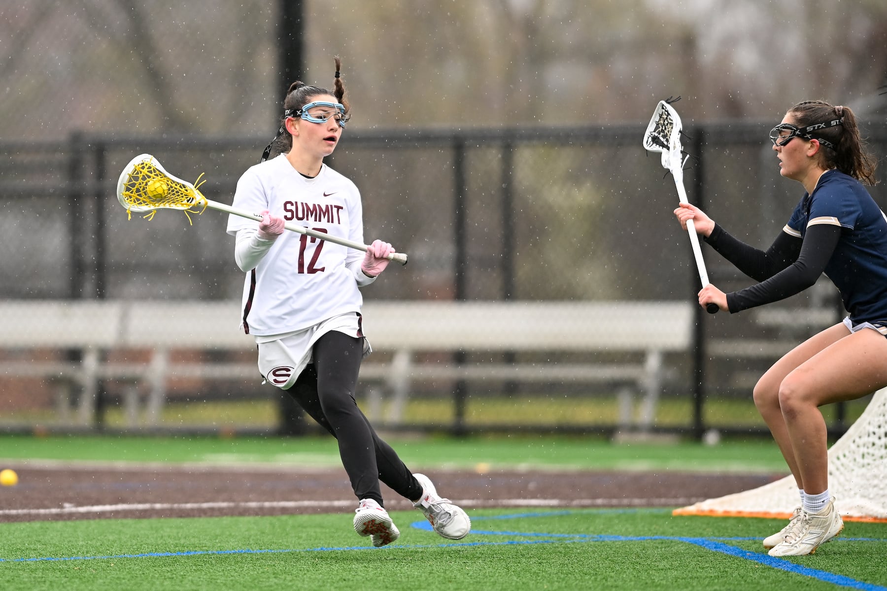 Sloane Ricciuti (12) of Summit looks to pass the ball over defender Beatrice Burton (4) of Oak Knoll during the girls lacrosse game between Oak Knoll and Summit at Oak Knoll High School in Chatham, NJ on Saturday, April 12, 2025.