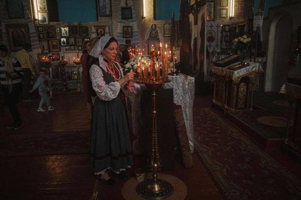 A woman lights a candle during the celebration of Orthodox...