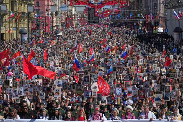People carry portraits of relatives who fought in World War...
