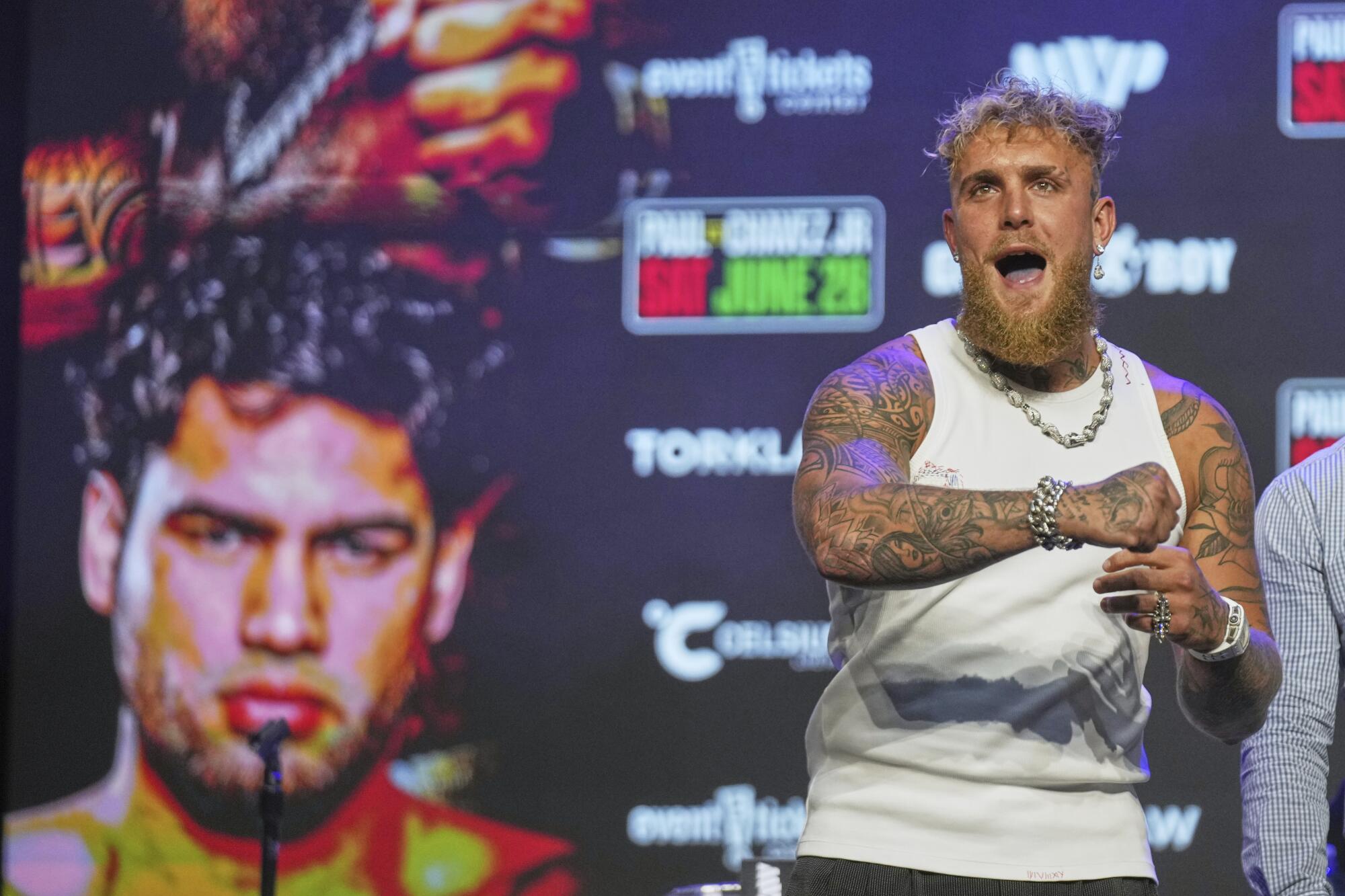 Boxer Jake Paul swings his arm in the air after challenging Julio César Chávez Jr., during a news conference.