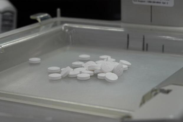 Pills sit in the tray of a pill-counting machine 