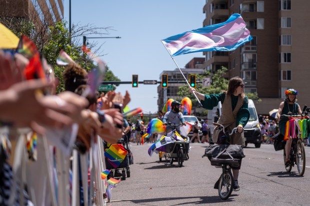 A Denver Pride Parade participant waves the transgender pride flag...