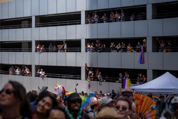 Attendees watch the Denver Pride Parade from a parking garage...
