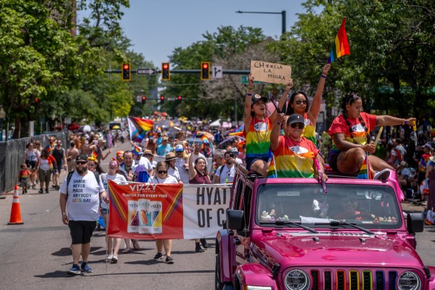 A participant holds up a sign as others wave pride...