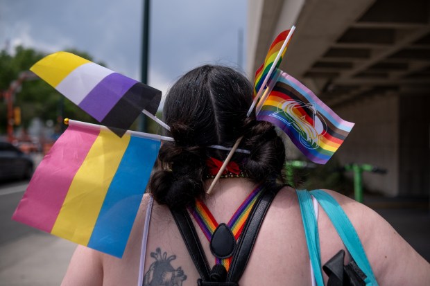 A Denver Pride Parade attendee sports various LGBTQ+ flags in...