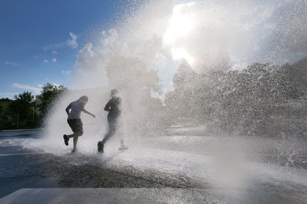 Young people cool off in the spray of an open hydrant on the West Side of Chicago as the temperature reaches 100 degrees on June 26, 2025.(Terrence Antonio James/Chicago Tribune)