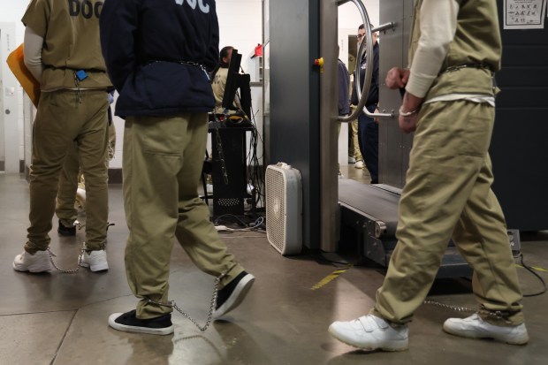 Under the watch of Cook County sheriff's officers, inmates walk toward a bus for transportation from Cook County Jail to various courthouses on April 16, 2025. (Antonio Perez/Chicago Tribune)