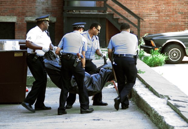 Chicago police officers remove the body of man from the...