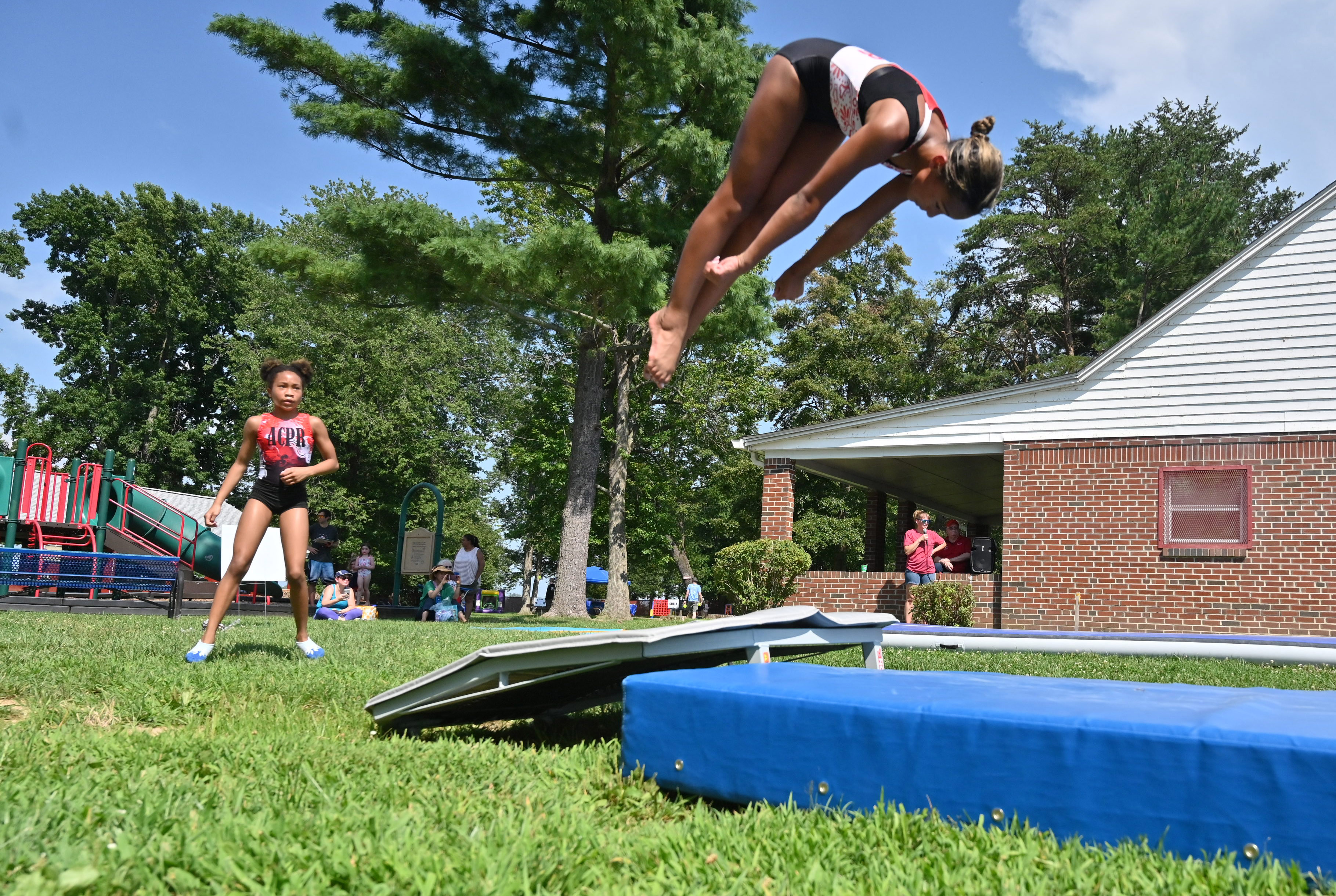 Madison Effinger, left, waits her turn as she watches fellow ACPR gymnast Ella Pass vault into the air during Harford County Parks and Recreation Day at Flying Point Park on Friday. (Brian Krista/Staff)