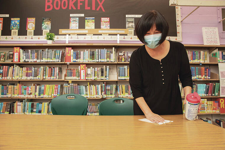 STAR-ADVERTISER / 2021
                                Laurie Chang, a curriculum coordinator and instructional coach for Aliiolani Elementary School, adheres to state COVID-19 guidance as she sanitizes a desk at the schools library in 2021.