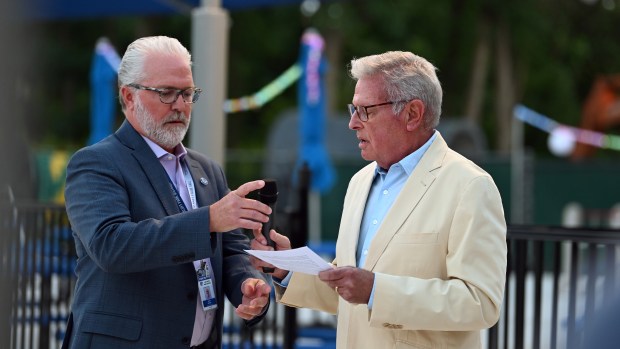 Left, Lake Bluff Park District Executive Director John Bealer hands the microphone over to Paul Greenfield of Lake Bluff, president of the Lake Bluff Park District Board of Commissioners, during the remarks portion of the VIP Pool Party at Blair Park pool in Lake Bluff on Aug. 26, 2025. (Karie Angell Luc/Pioneer Press)