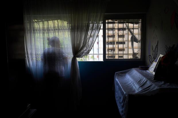 Syntia Caceres looks out the window of her home while...