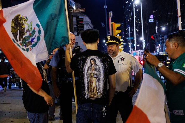Chicago Police ask 20-year-old Noel to remove the wooden rod attached to his Mexican flag near Michigan Avenue as people and vehicles gather while celebrating Mexican Independence Day, Sept. 13, 2025. (Armando L. Sanchez/Chicago Tribune)