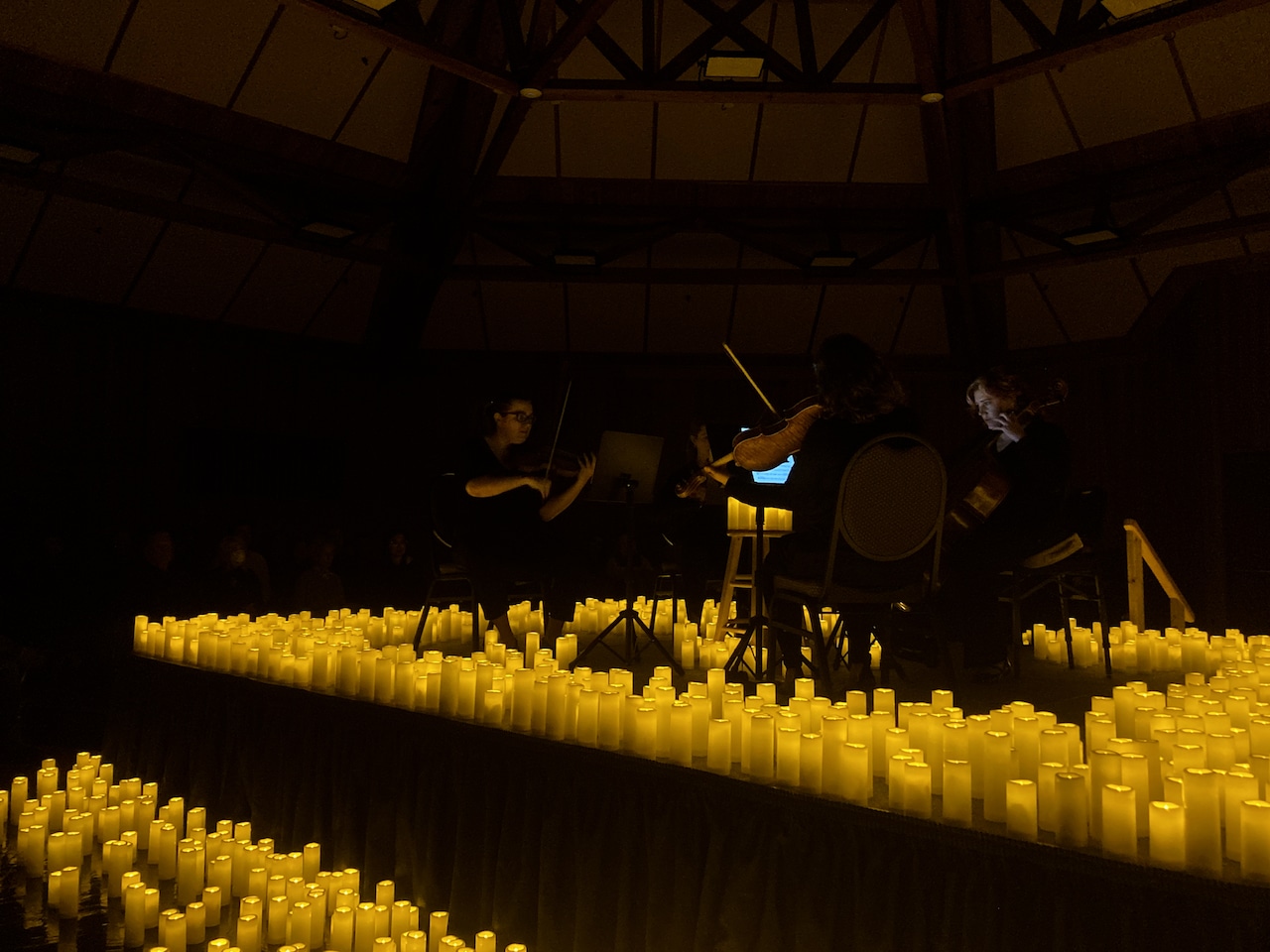 thousands of glowing candles surround a stage in the center of a dark room