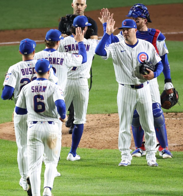 Cubs left fielder Ian Happ celebrates with teammates in the...