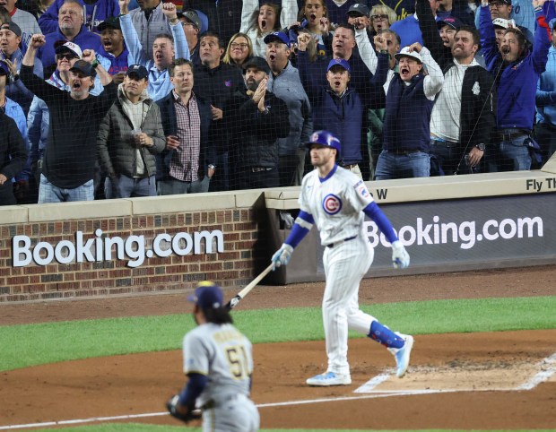 Fans cheer as Cubs left fielder Ian Happ watches his...