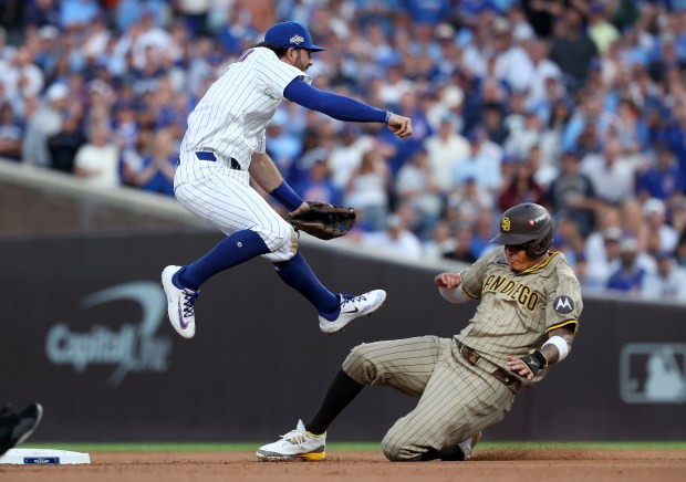 Cubs shortstop Dansby Swanson leaps over Padres third baseman Manny...