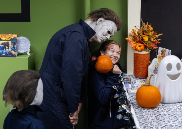 Sadie McDonald, 14, tries to defend herself with a pumpkin while Evan Zimmerman, dressed as Michael Myers, offers her a hug during a horror movie trivia night on Oct. 9. 2025, at D-Town Energy in Decatur, Indiana. Zimmerman does not talk when in costume and emulates Michael Myers' movements like in the movie Halloween. (Dominic Di Palermo/Chicago Tribune)