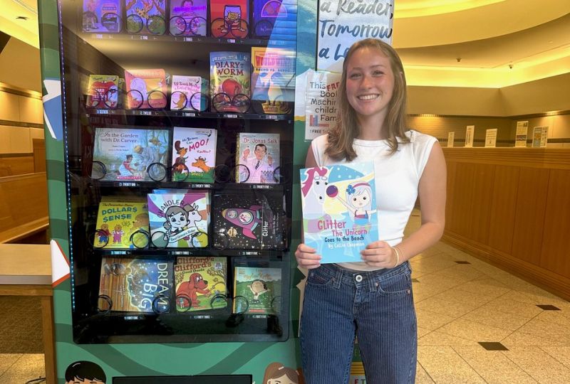 Girl holding book near vending machine