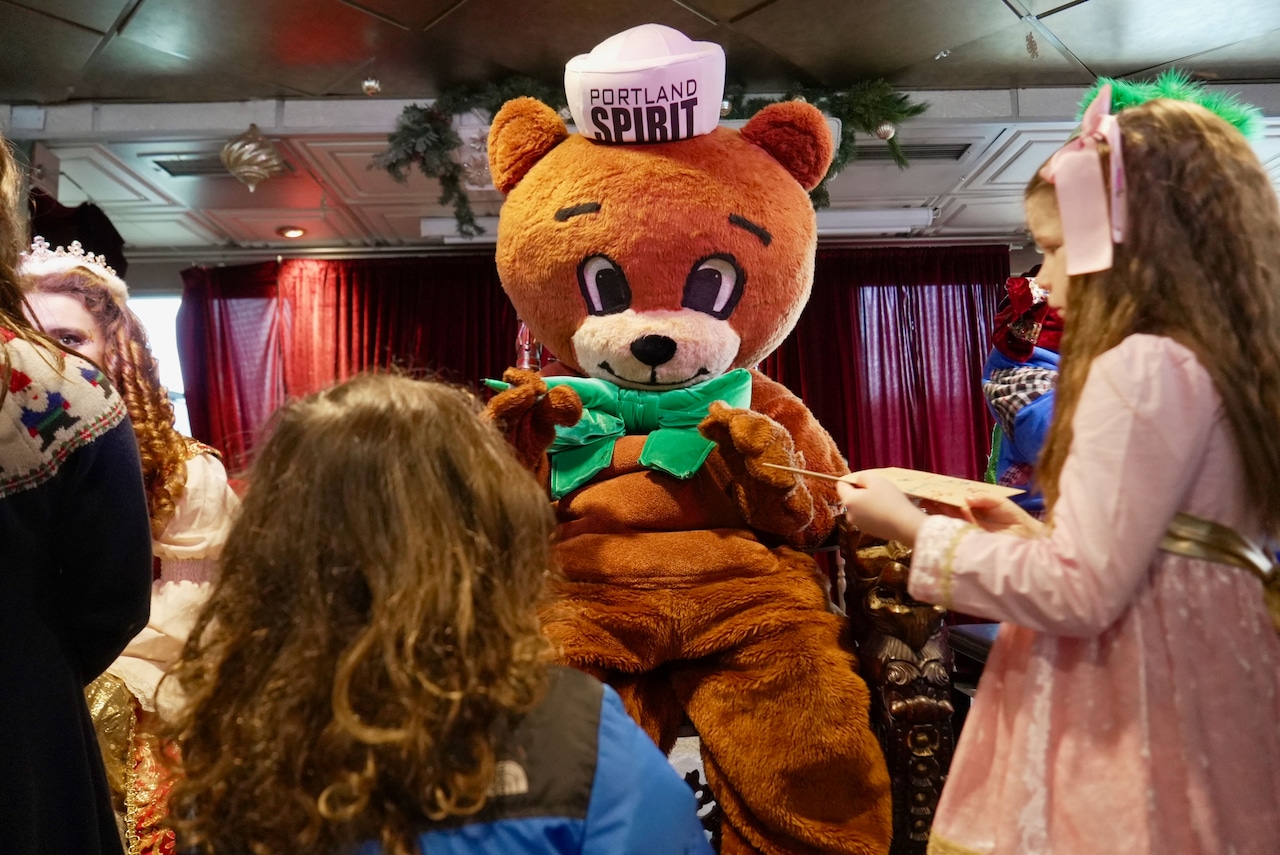 the Cinnamon Bear, seated on a throne, waves and prepares to sign autographs