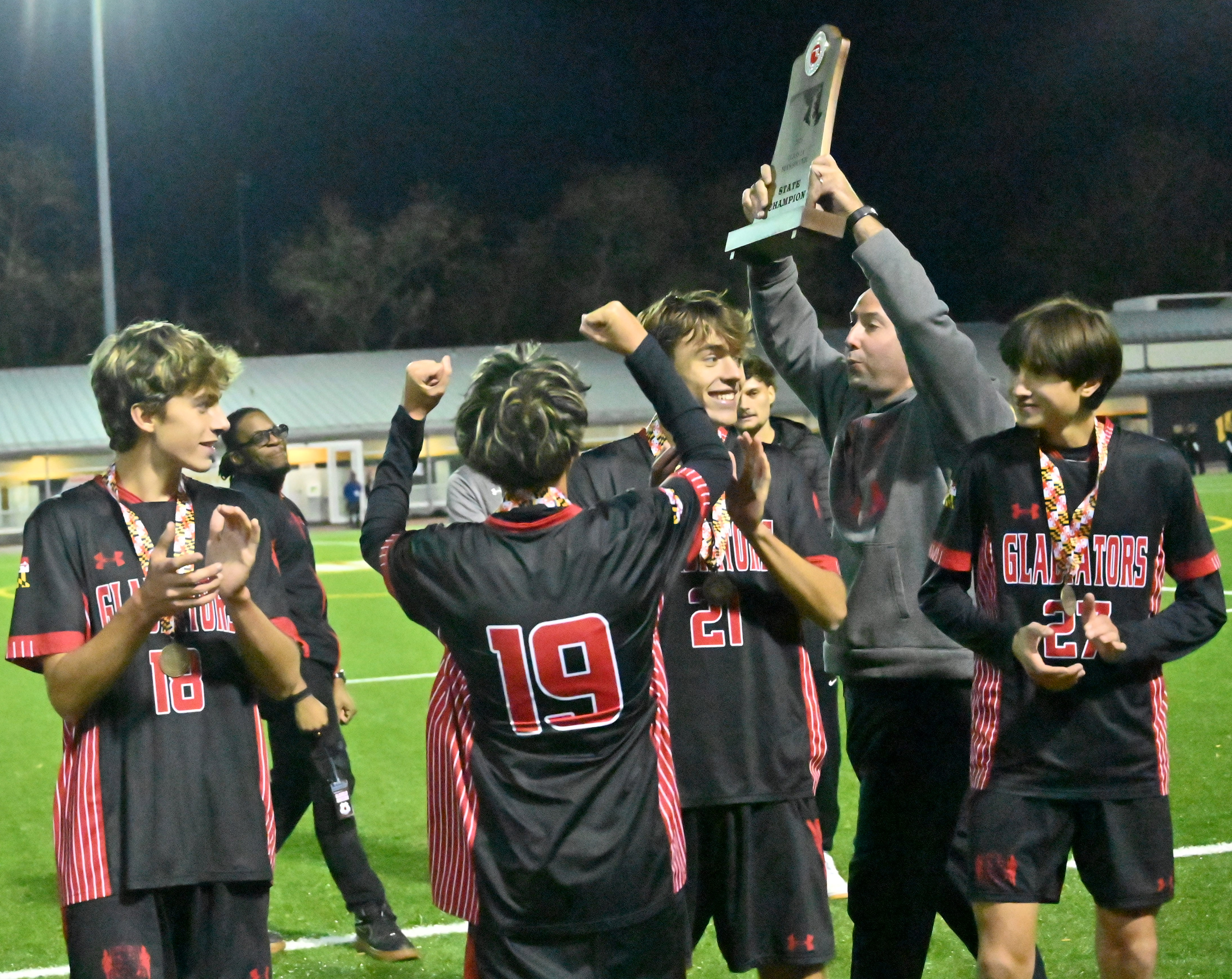 Glenelg head coach Joe Osborne presents the championship trophy to his team following their win over Fallston during the Class 2A boys soccer state championship game at UMBC on Thursday. (Brian Krista/Staff)