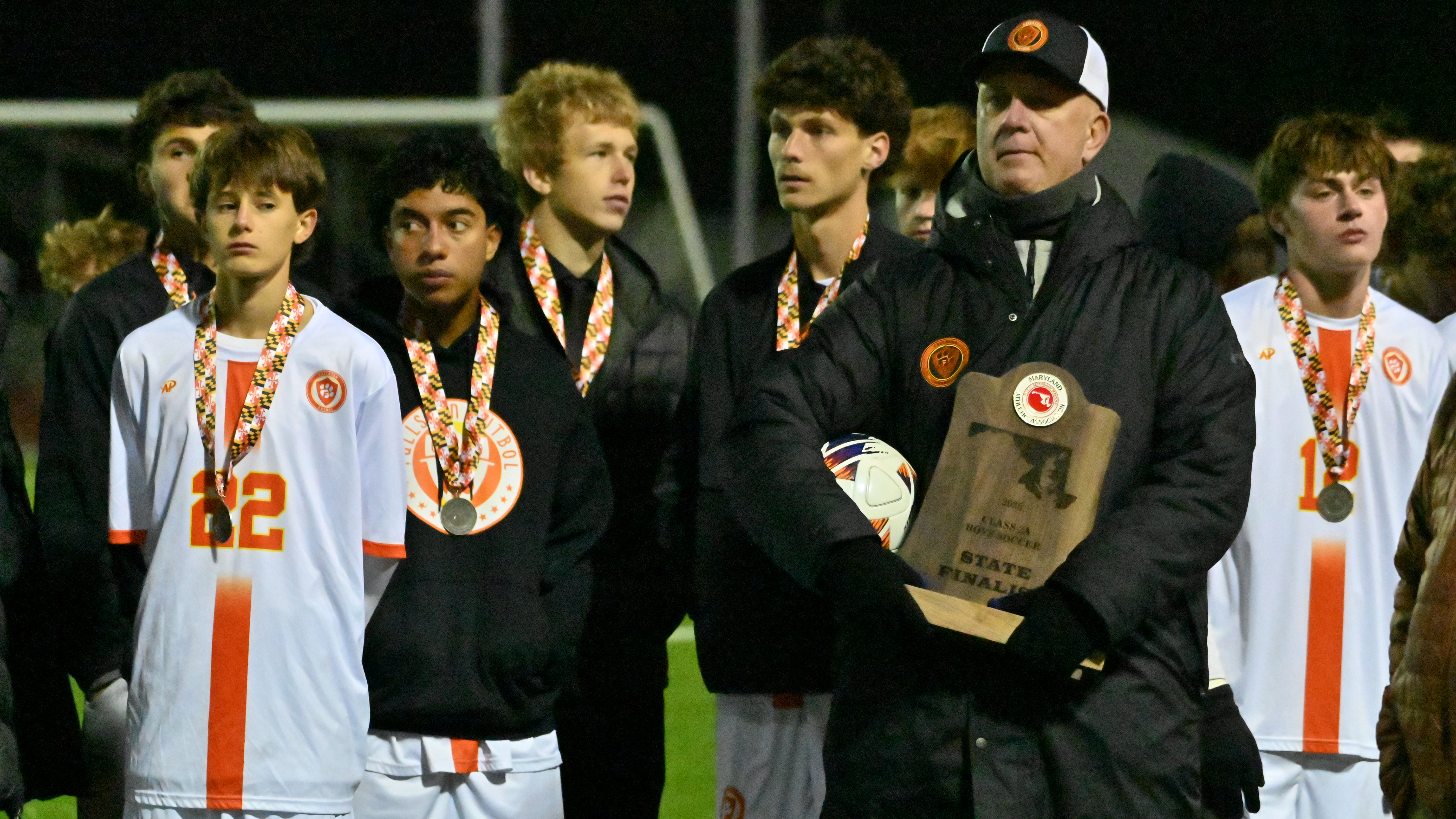 Fallston head coach Christopher Hoover holds the finalist trophy as he stands with his team following their loss to Glenelg during the Class 2A boys soccer state championship game at UMBC on Thursday. (Brian Krista/Staff)