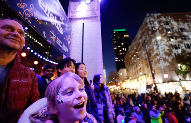 Clementine Roberts, 9 and her Dad, Scott Roberts, left, from Lynnwood enjoy the holiday music during the downtown tree lighting celebration in Seattle on Friday, November 29, 2024.