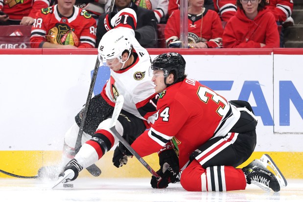 CHICAGO, ILLINOIS - OCTOBER 28: Shane Pinto #12 of the Ottawa Senators and Colton Dach #34 of the Chicago Blackhawks crash into the boards during the first period at the United Center on October 28, 2025 in Chicago, Illinois. (Photo by Michael Reaves/Getty Images)