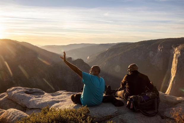 FILE - Visitors watch a sunset on rock ledge near Taft Point in Yosemite National Park, Calif., Oct. 30, 2025. (Stephen Lam/San Francisco Chronicle via AP, File)