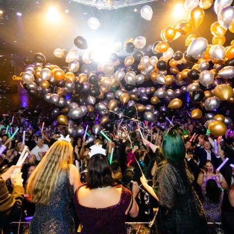 people celebrate the new year with glow sticks and a balloon drop at a party