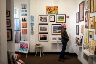 man looking at framed art hanging on art studio walls