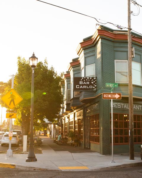 a green building at a street corner bathed in sunlight