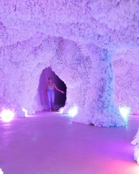 A person explores brightly lit, highly textured cave-like structure.