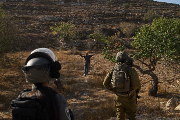 An Israeli settler gestures as Israeli soldiers block access for...