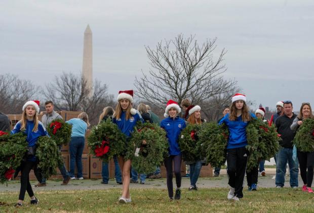 FILE - Volunteers walk with holiday wreaths to lay at headstones in Arlington National Cemetery during Wreaths Across America Day in Arlington, Va., Dec. 18, 2021. (AP Photo/Gemunu Amarasinghe, File)
