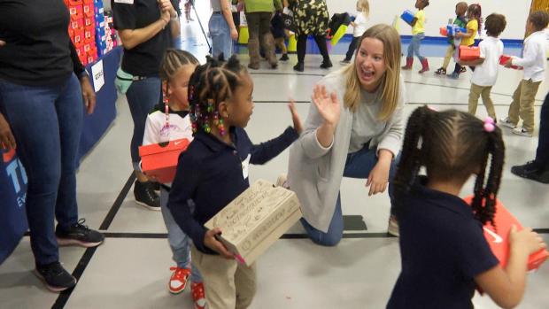 FILE - A volunteer waves to a student as she waits in line at Miles Intermediate Elementary School in Atlanta after receiving new shoes from Mercedes-Benz USA, as a part of their Season to Shine holiday program, on Dec. 7, 2022. (AP Photo/Sharon Johnson, File)