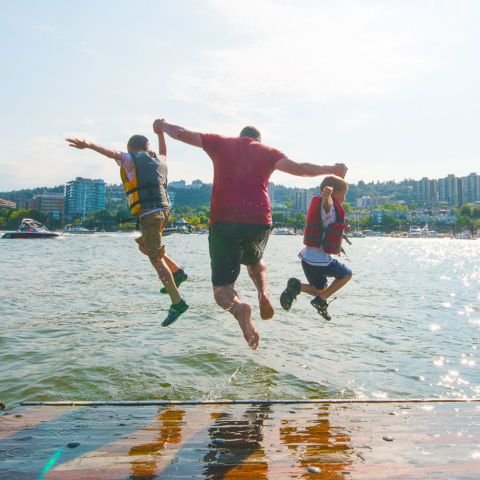 three people mid-jump into a river