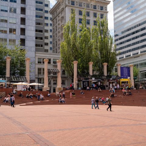 people sitting, walking in brick plaza with white columns