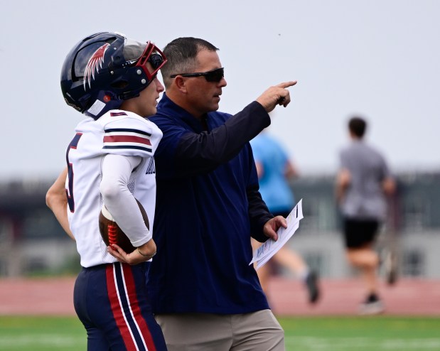 Dakota Ridge head coach Jeremiah Behrendsen, right, talks with his son, quarterback Kellen Behrendsen (5), during practice at Dakota Ridge High School in Littleton on Friday, Aug. 15, 2025. (Photo by Andy Cross/The Denver Post)