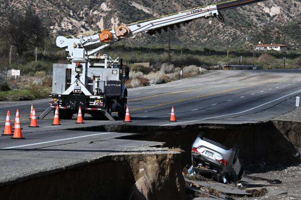A car is flipped over along a storm-damaged road after a series of storms on Thursday, Dec. 25, 2025, near Phelan, Calif.