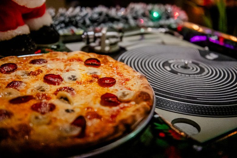 a pizza sits next to a turntable