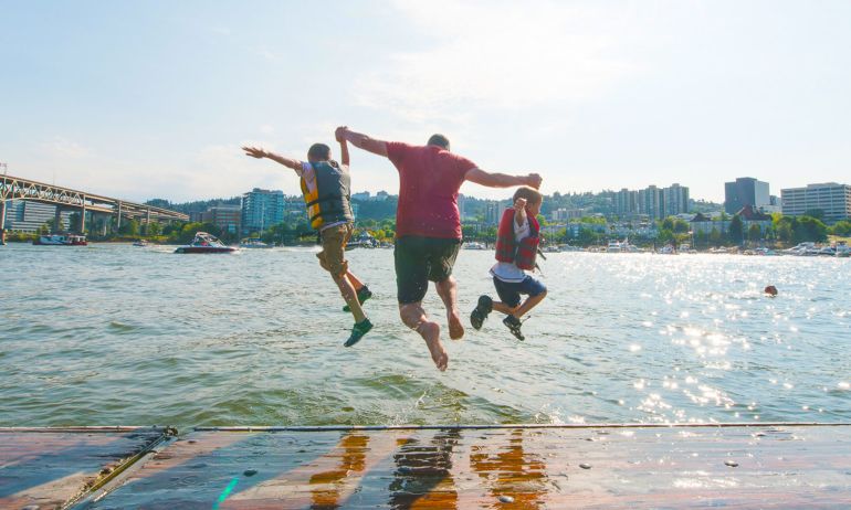 three people mid-jump into a river