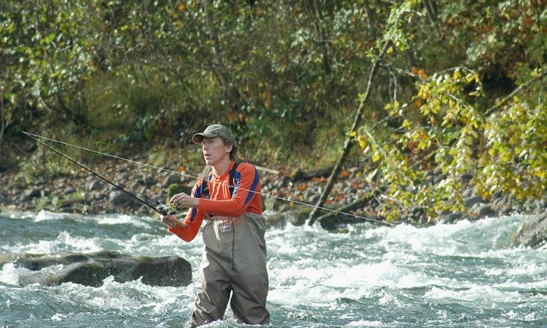 a fisherman flyfishing in a river