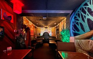 various deep booths line the walls of a warmly lit bar