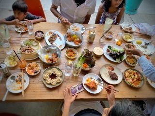 people sit around a vast spread of Korean food arrayed on a wooden table