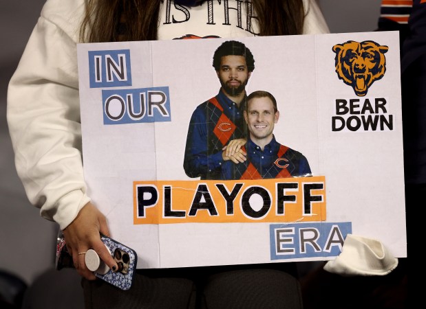 A fan holds a poster featuring images of Caleb Williams and Ben Jonnson as players warm up for a game a NFC wild-card game between the Chicago Bears and the Green Bay Packers at Soldier Field in Chicago on Jan. 10, 2026. (Chris Sweda/Chicago Tribune)