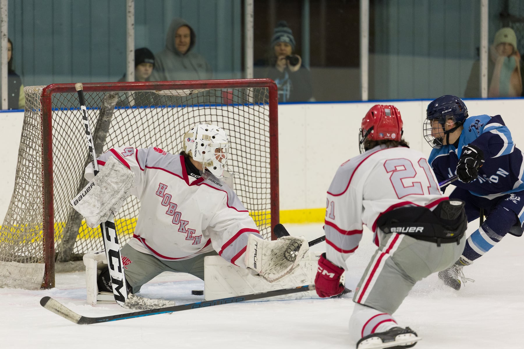 Sammy Zapotoka of A.L. Johnson (right) pokes the puck past Hoboken goalie Christian Ferullo (4) in Sunday's high school boys ice hockey showdown in Roselle. Johnson out-skated the Redwings 4-1.  01/11/2026