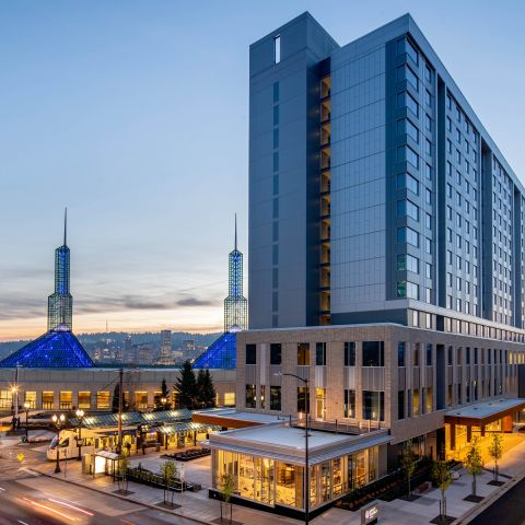 Exterior view of the Hyatt Regency Portland with the twin spires of the Oregon Convention Center in the background