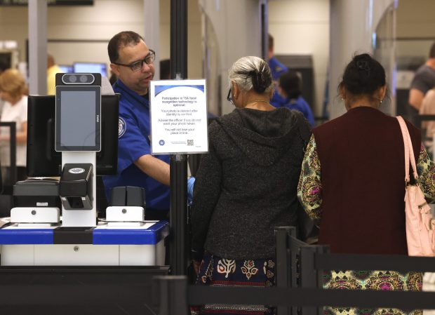 Air travelers go through security after passing by signage informing them that they may be denied access or subject to additional security measures without a REAL ID at Midway Airport on May 7, 2025. (Antonio Perez/Chicago Tribune)