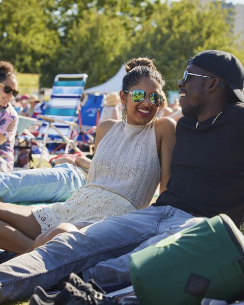 two people sit together in the sunshine in the middle of a crowd